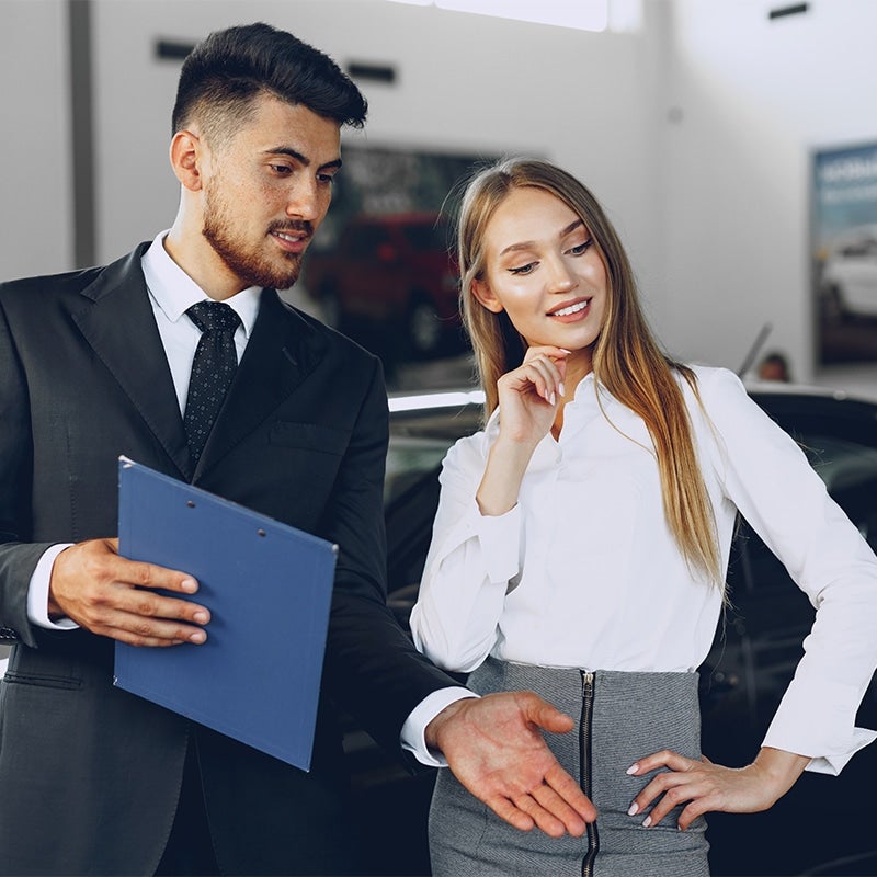 Customer and salesperson inspecting car in showroom