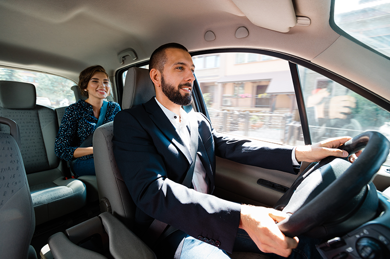 Man driving while woman sits in the back seat
